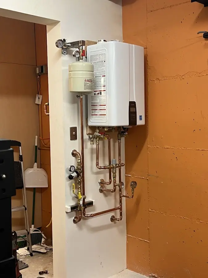 Plumbing technician inspecting water heater connections in Fletcher